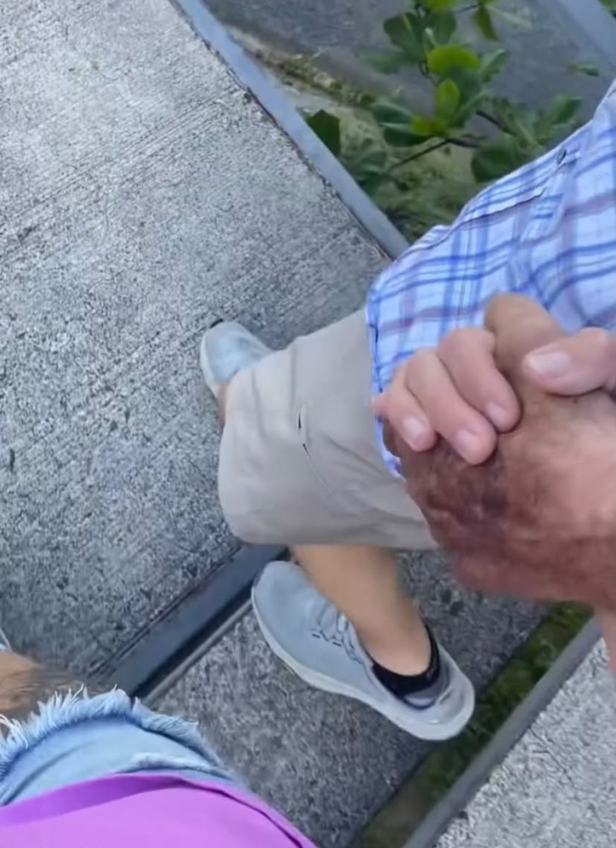 A caregiver steadies a client's hand on a walk